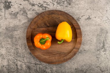 Two sweet bell peppers placed on wooden plate. High quality photo