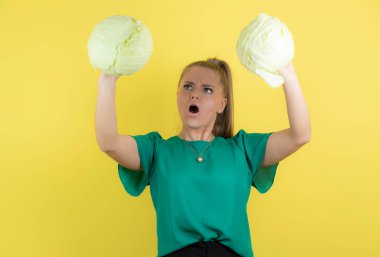 Sarı duvarın üzerinden ağır taze lahanalara bakan genç ev kadınının görüntüsü. Yüksek kalite fotoğraf