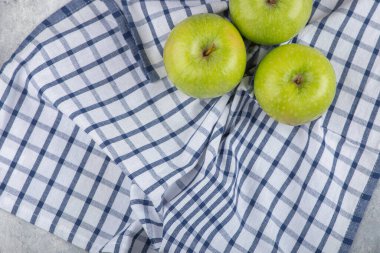 Taş zeminde masa örtüsü olan üç sağlıklı yeşil elma. Yüksek kalite fotoğraf