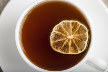 White cup of black tea with lemon slice on stone background. High quality photo