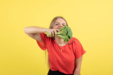 Büyük yeşil brokoli yiyen güzel bir kadın manken resmi. Yüksek kalite fotoğraf