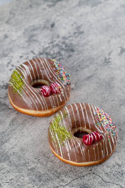 Çikolata kaplı donutlar, taştan arka planda serpiştirilmiş meyve parçaları ile süslenmiş. Yüksek kalite fotoğraf