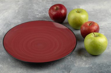 Empty red plate with red and green apples on stone background. High quality photo