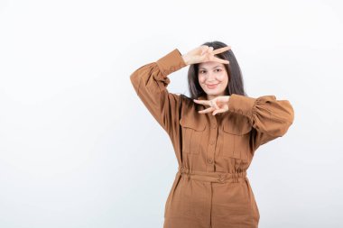 Beyaz duvara karşı zafer işareti gösteren esmer bir kadın modeli. Yüksek kalite fotoğraf