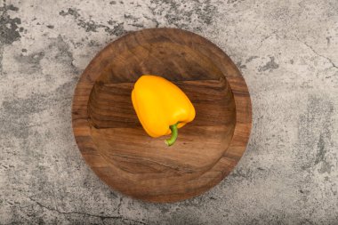 Yellow sweet bell pepper placed on wooden plate. High quality photo