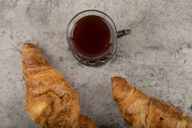 İki lezzetli tereyağlı kruvasan ve bir bardak çay. Yüksek kalite fotoğraf