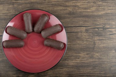 Tahta arka planda izole edilmiş çikolatalı tatlı kekleri olan kırmızı tabak. Yüksek kalite fotoğraf