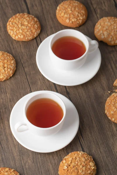 Biscoitos Aveia Com Sementes Xícaras Brancas Chá Preto Superfície Madeira — Fotografia de Stock