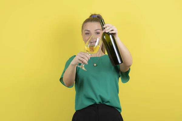 年轻美丽的女人 拿着一杯白葡萄酒 在黄色的背景上欢快地感觉着 高质量的照片 — 图库照片