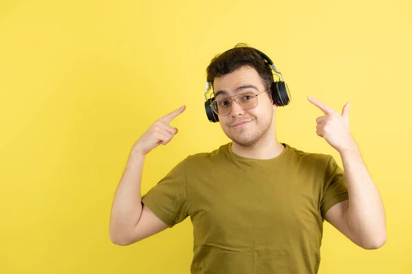黄色の壁の上に立ってヘッドフォンでハンサムな若い男 高品質の写真 — ストック写真