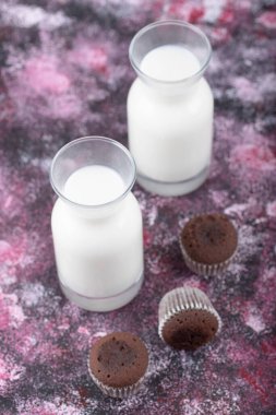 Mini çikolatalı kekler ve mor arka planda bir bardak taze süt. Yüksek kalite fotoğraf
