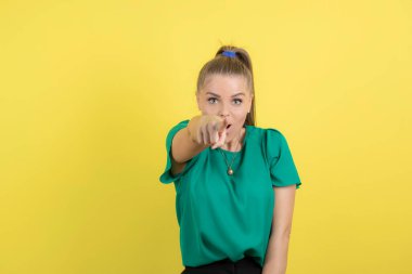 Genç ve güzel bir kadın sarı arka planda kameraya bakıyor. Yüksek kalite fotoğraf