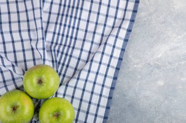Taş zeminde masa örtüsü olan üç sağlıklı yeşil elma. Yüksek kalite fotoğraf