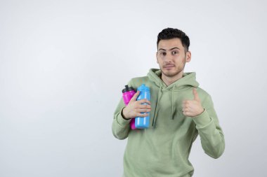 Renkli su şişeleriyle baş parmağını gösteren genç bir adam resmi. Yüksek kalite fotoğraf