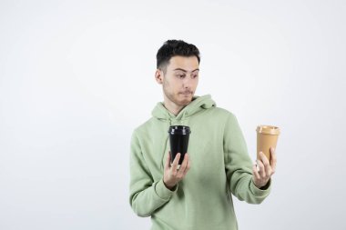 Genç yakışıklı adam beyaz kahve fincanlarına bakıyor. Yüksek kalite fotoğraf