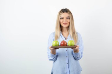 Tahtada yeşil ve kırmızı elmalar tutan sarışın bir kızın portresi. Yüksek kalite fotoğraf