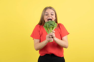 Büyük yeşil brokoli yiyen güzel bir kadın manken resmi. Yüksek kalite fotoğraf