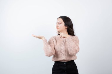 Ayakta duran ve avuç içini beyaz duvara gösteren güzel bir kadın resmi. Yüksek kalite fotoğraf