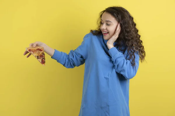 Foto Una Bella Ragazza Che Guarda Pezzo Pizza Sfondo Giallo — Foto Stock