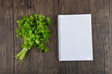 Sağlıklı yeşil maydanoz yaprakları ve tahta arka planda boş defter. Yüksek kalite fotoğraf