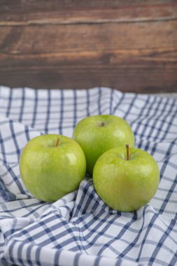 Taş zeminde masa örtüsü olan üç sağlıklı yeşil elma. Yüksek kalite fotoğraf