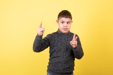 Gayri resmi giyinmiş, ayakta duran ve zafer işareti yapan sevimli bir çocuğun fotoğrafı. Yüksek kalite fotoğraf