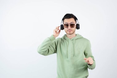 Kulaklıklı genç yakışıklı bir adamın beyazın üzerinde duruşu. Yüksek kalite fotoğraf
