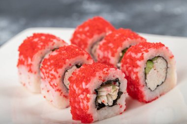 Beyaz Kaliforniya suşisi tabakası taştan arka planda yuvarlanıyor. Yüksek kalite fotoğraf