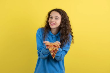 Sarı arka planda pizza gösteren genç bir kızın portresi. Yüksek kalite fotoğraf