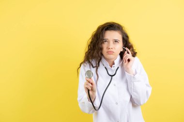 Doktor üniformalı genç bir kız steteskop kullanıyor ve kalp atışlarını dinliyor. Yüksek kalite fotoğraf