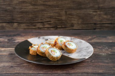 Ahşap yüzeye yerleştirilmiş lezzetli tempura rulo mermer tabak. Yüksek kalite fotoğraf