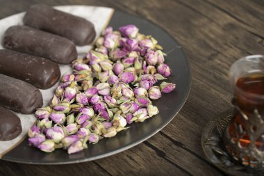 Bir bardak siyah çayın yanında çikolata çubukları ve gül çiçekleri olan bir tabak. Yüksek kalite fotoğraf