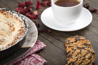 Hindistan cevizi parçalı bir tabak tatlı turta, bisküvi ve ahşap zemin üzerinde bir fincan çay. Yüksek kalite fotoğraf