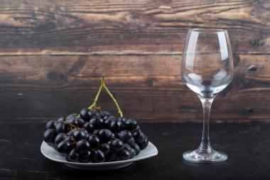 Siyah arka planda beyaz şarap ve siyah üzüm tabağı. Yüksek kalite fotoğraf