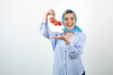 Mavi şallı güzel bir kadın elinde kırmızı taze domates tutuyor. Yüksek kalite fotoğraf