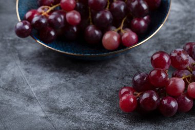 Mavi kase taştan arka planda sulu kırmızı üzümlerle dolu. Yüksek kalite fotoğraf