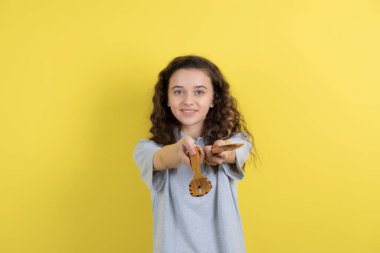 Sarı arka planda duran mutfak aletleriyle güzel bir genç kız. Yüksek kalite fotoğraf