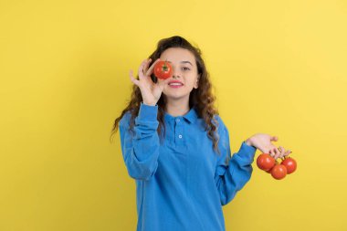 Mavi kazaklı genç kız kırmızı domateslerle poz veriyor. Yüksek kalite fotoğraf