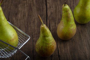 Delicious green pears on shopping card on wooden background. High quality photo