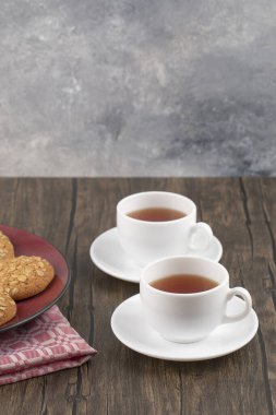 Kırmızı tabak ve yulaflı kurabiyeler ahşap masada bir fincan çay. Yüksek kalite fotoğraf
