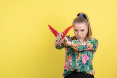 Sarı duvara kırmızı biberle poz veren sarışın bir manken. Yüksek kalite fotoğraf