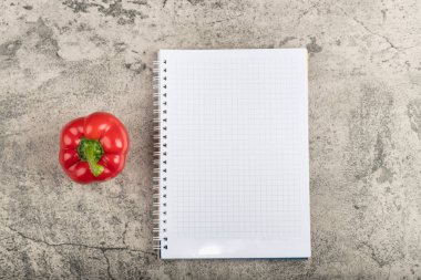 Kırmızı dolmalık biber ve taş yüzeyde boş defter. Yüksek kalite fotoğraf