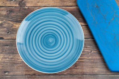Empty blue dinner plate and blue board on wooden background. High quality photo