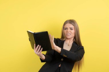 Resmi kıyafetli güzel bir kadın sarı arka plan notlarını kontrol ediyor. Yüksek kalite fotoğraf