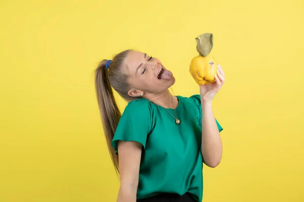 Obraz Młodej Samicy Jedzącej Dojrzałe Owoce Pigwy Nad Żółtą Ścianą — Zdjęcie stockowe