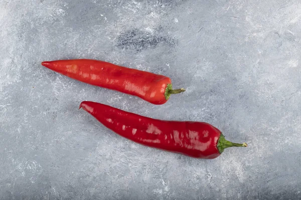 Mermer zemin üzerine iki kırmızı biber yerleştirilmiş. Yüksek kalite fotoğraf