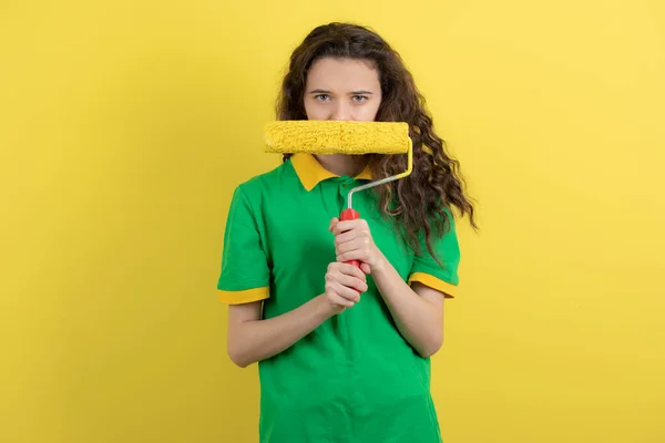 Kép Göndör Lány Zöld Pólóban Kezében Festék Görgő Sárga Háttér — Stock Fotó