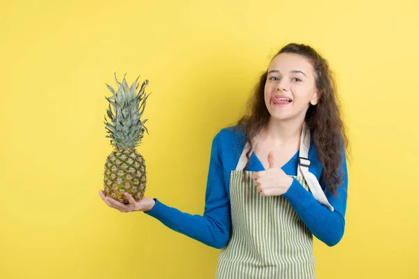Młoda Nastolatka Fartuchu Trzymająca Dojrzały Ananas Żółtej Ścianie Wysokiej Jakości — Zdjęcie stockowe