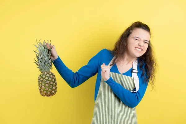 Młody Kręcony Nastolatek Fartuchu Pokazujący Dojrzałego Ananasa Żółtej Ścianie Wysokiej — Zdjęcie stockowe