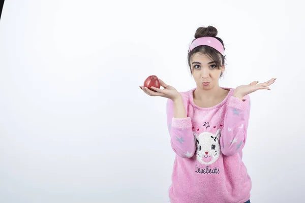 照片上 一个年轻的女孩在睡衣拿着一个红色的苹果果实 高质量的照片 — 图库照片